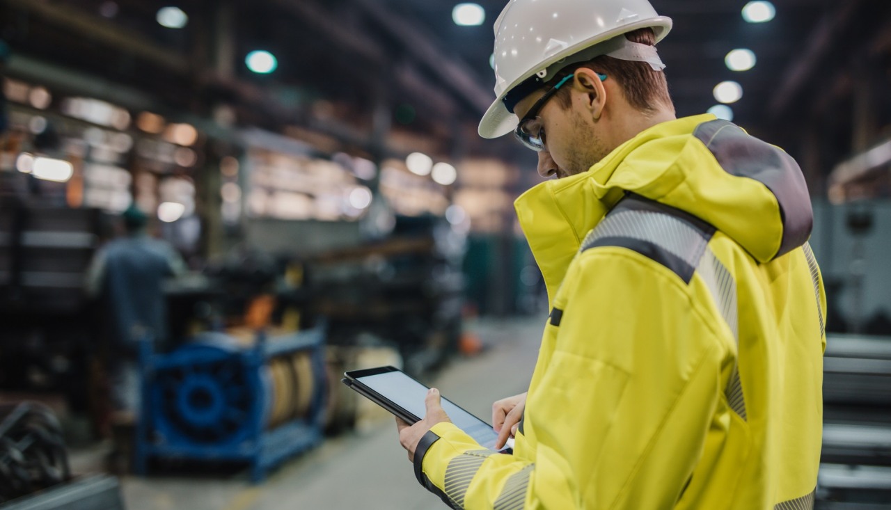 Male Engineer using digital tablet in factory.